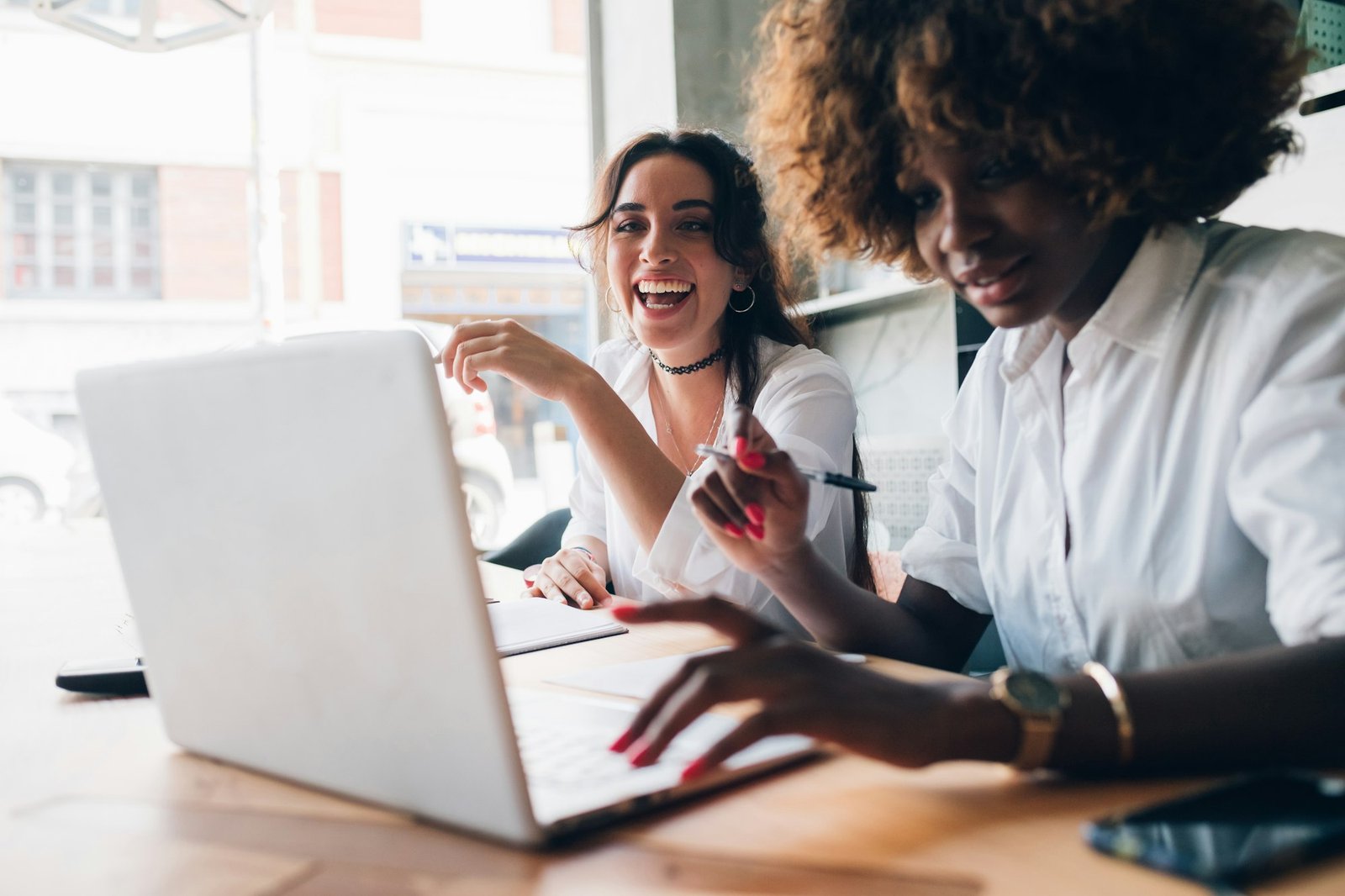 two multiracial young women studying and having fun in a co-working studio